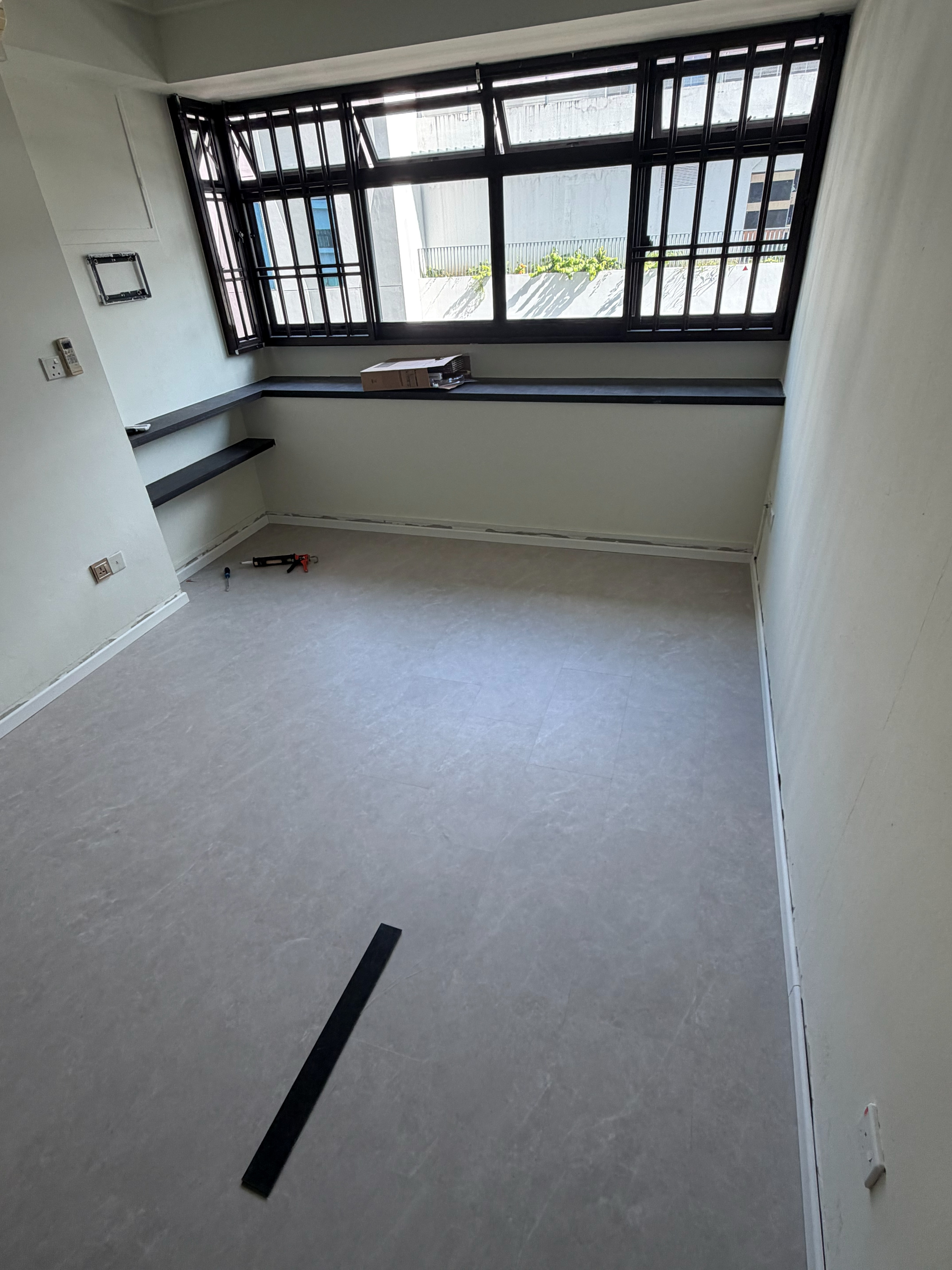 Grey wood-look vinyl flooring in an empty Singapore bedroom beside a large window